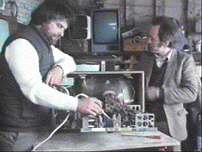 Rex repairs a TV as Tim looks on